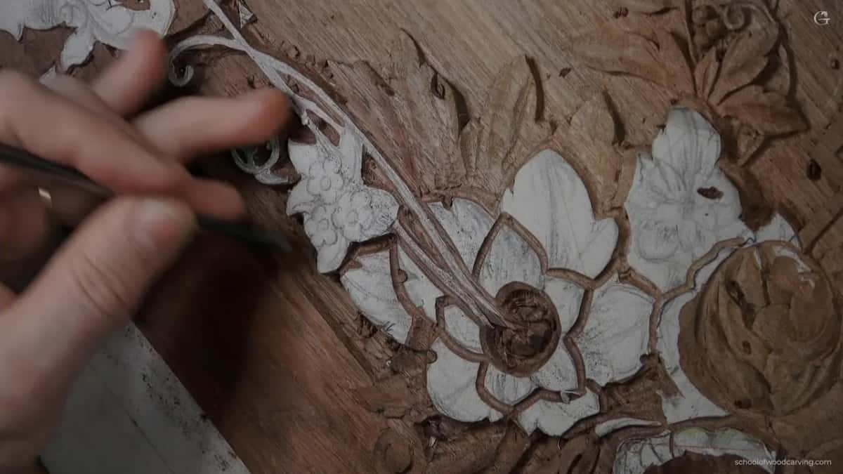 One hand holds a small tool at the edge of a paper-covered flower, close up.