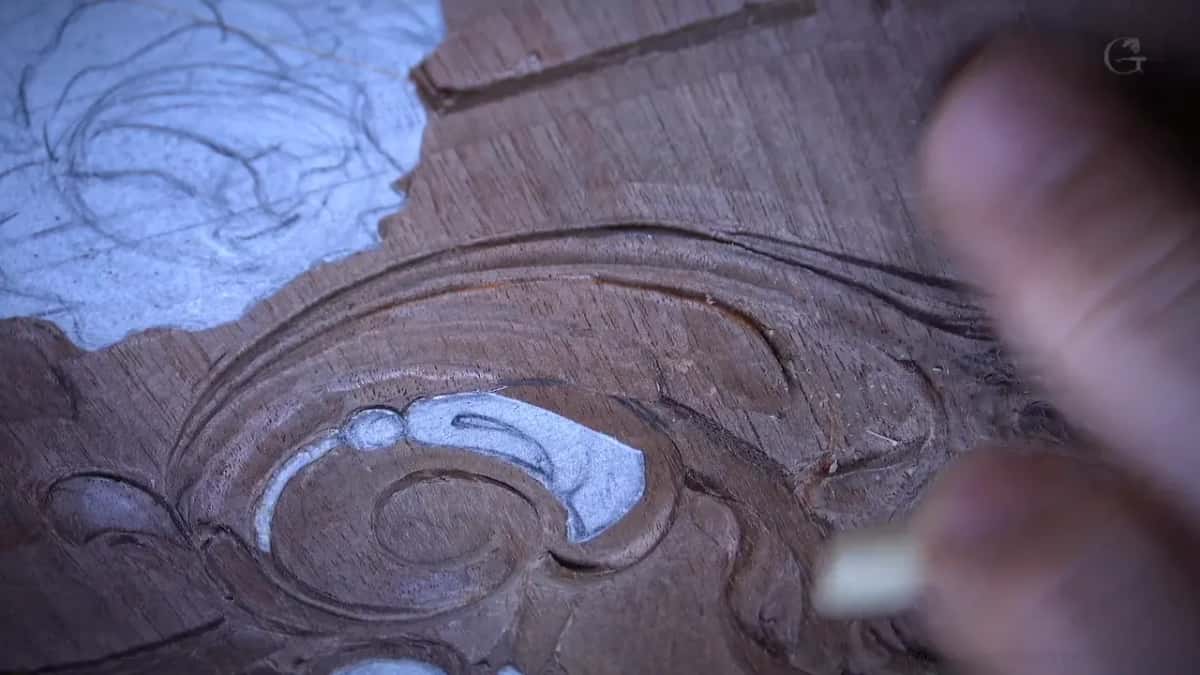 Blurred fingers and a pale reed tube over the scroll, its paper still on
