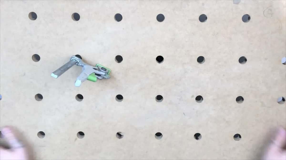 One small clamp left on the drilled bench board, hands just entering below
