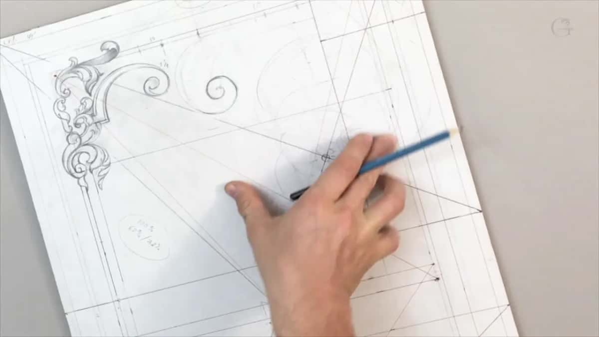 Right hand holding a blue pencil over the middle of the layout, palm resting on the paper
