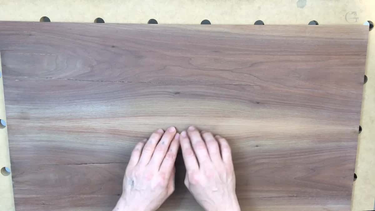 Two hands side by side, fingertips touching, low on the walnut