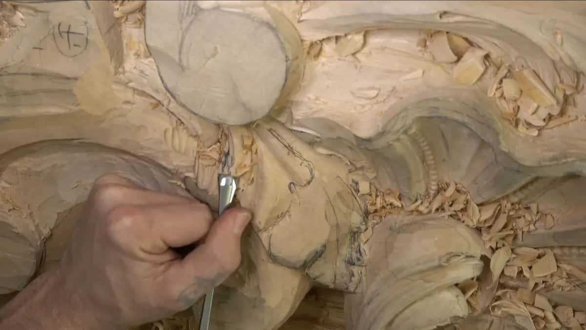 One hand keeps a gouge upright under the boss.
