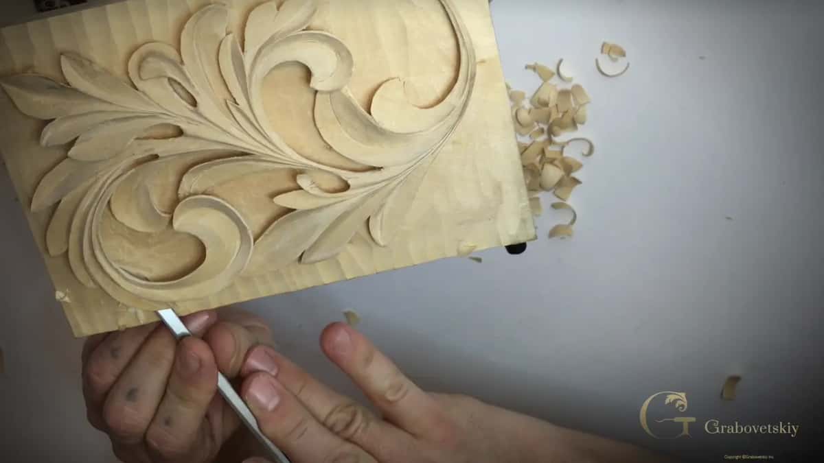 A narrow steel tool at the lower edge and a heap of shavings to the right of the board