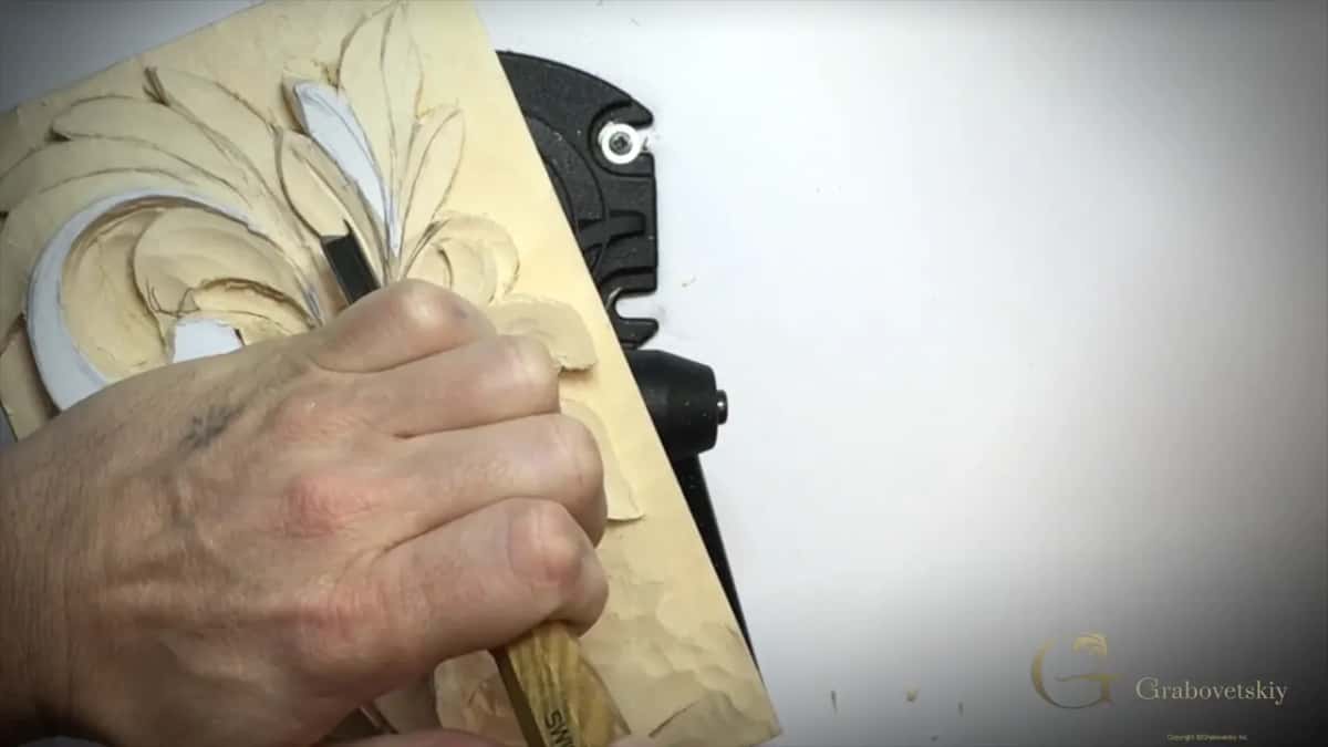 Fist round a long handle, its tool in a leaf near the top of the panel
