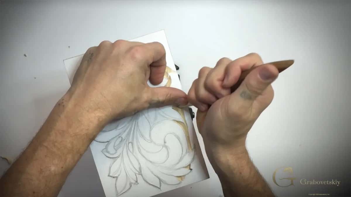 Thumb of the left hand right beside the blade at the panel edge