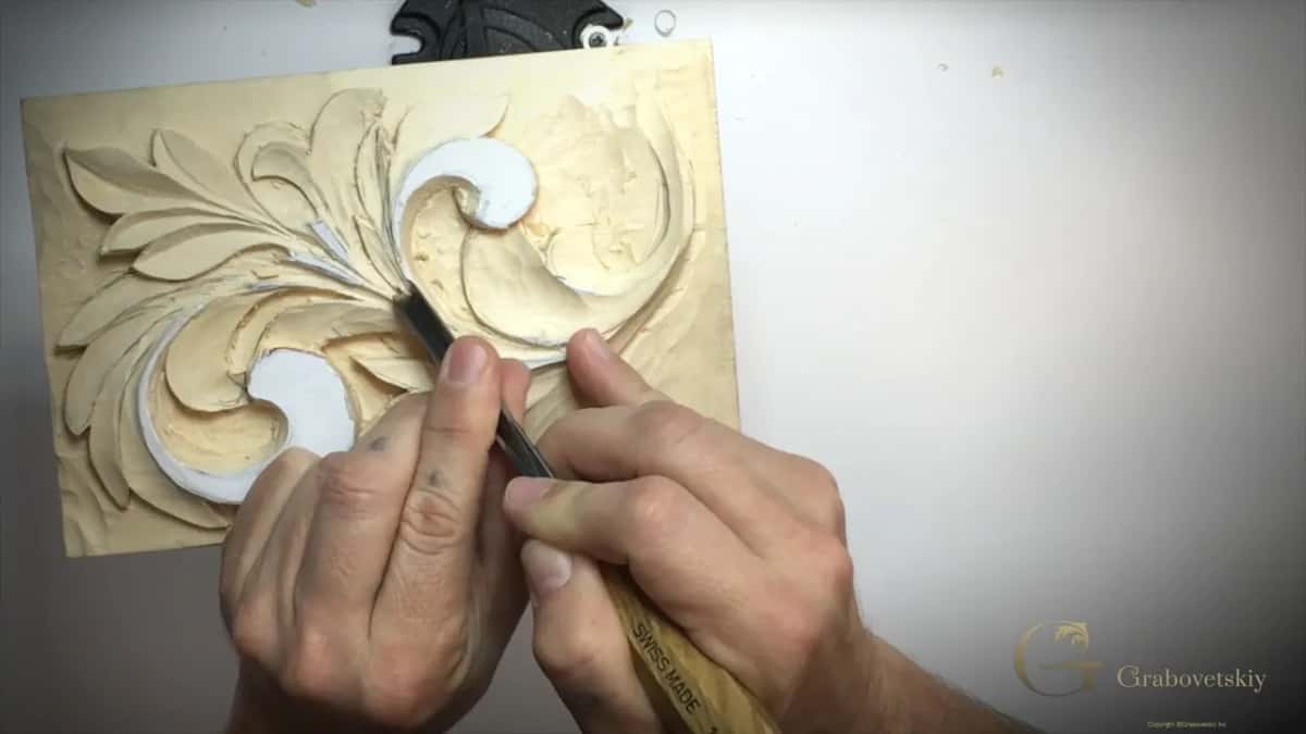 Both hands on a V tool between the two white curls