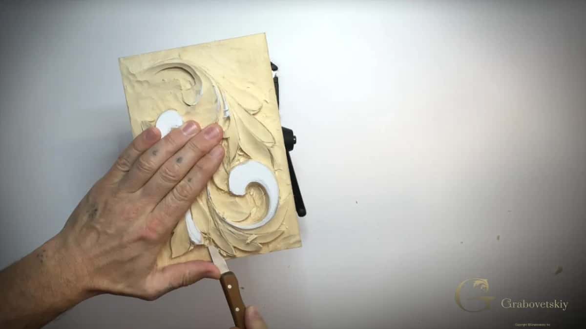 Whole panel from above, left hand flat on it, a knife near the bottom