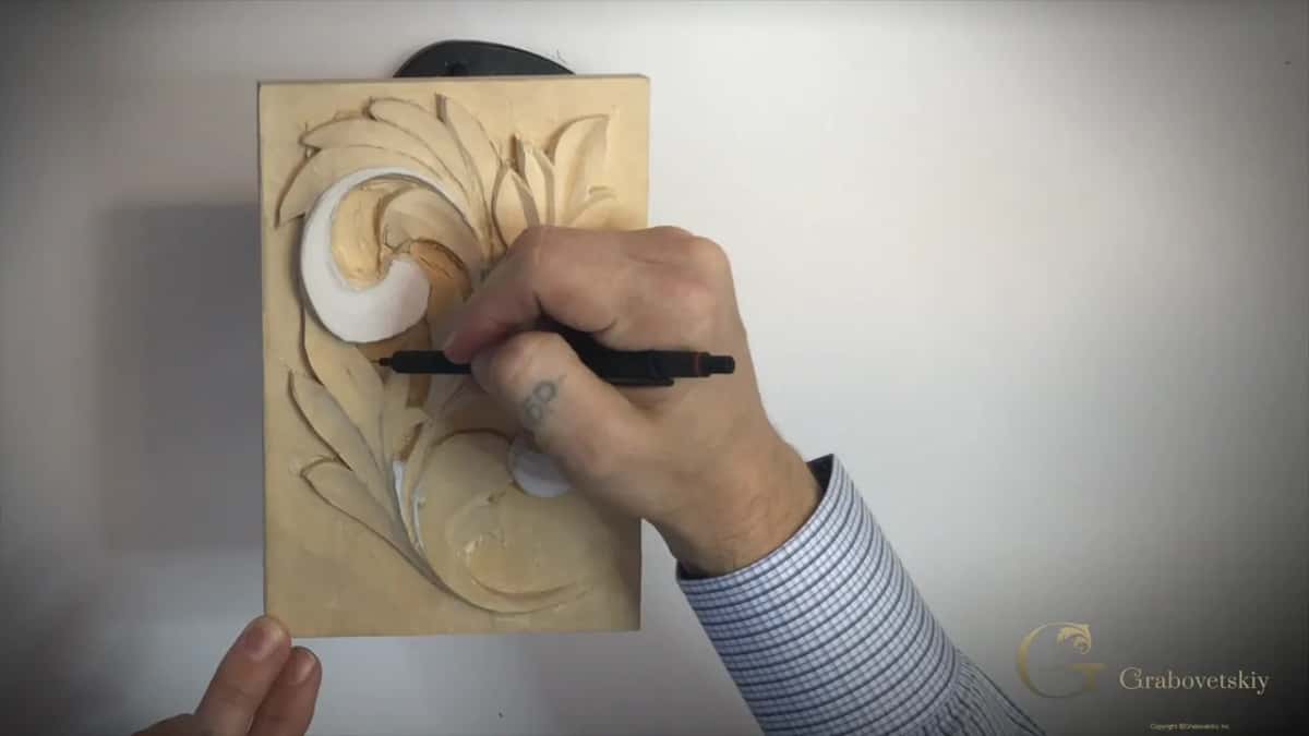 Black pen marking a lobe under the big top curl, fingers showing at the lower left