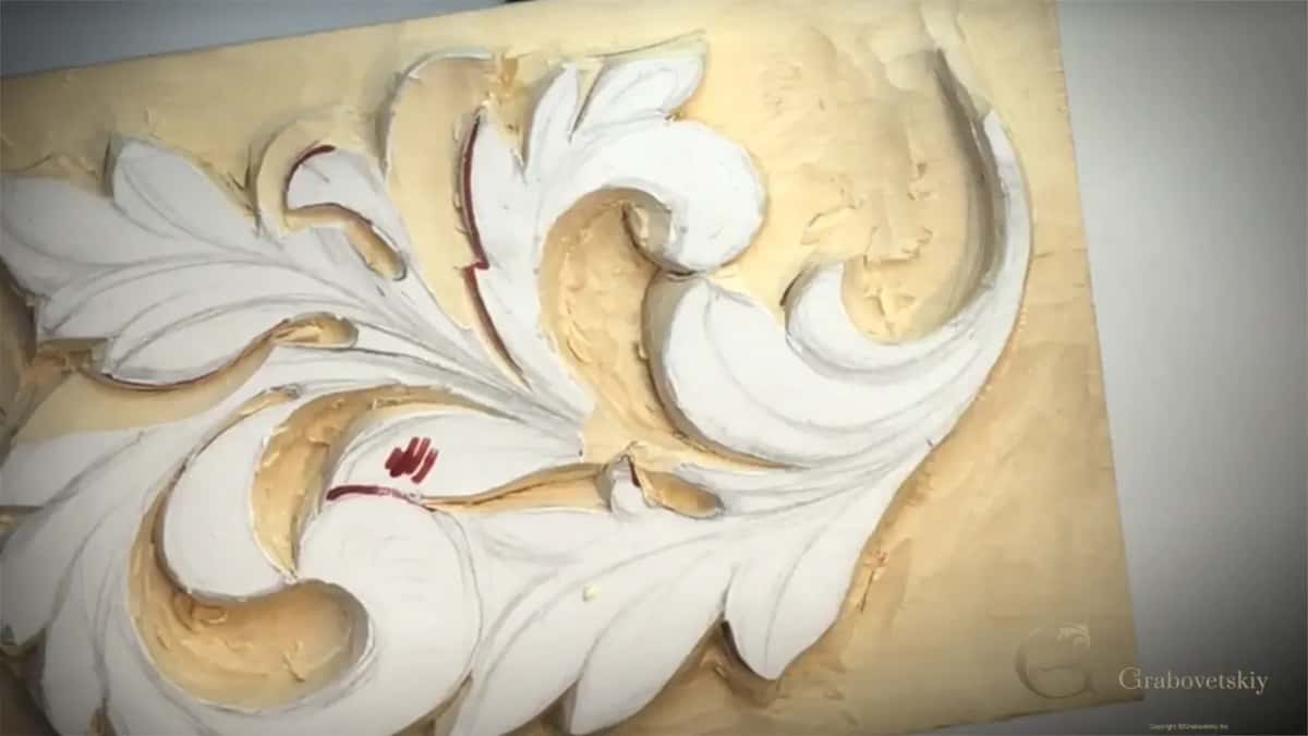 Close view of the half-carved leaf with no hands, red marker lines on the white paper