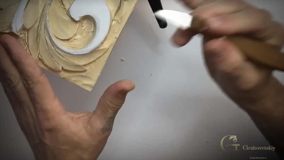 Knife lifted beside the top curl, the left hand open below it, chips on the table