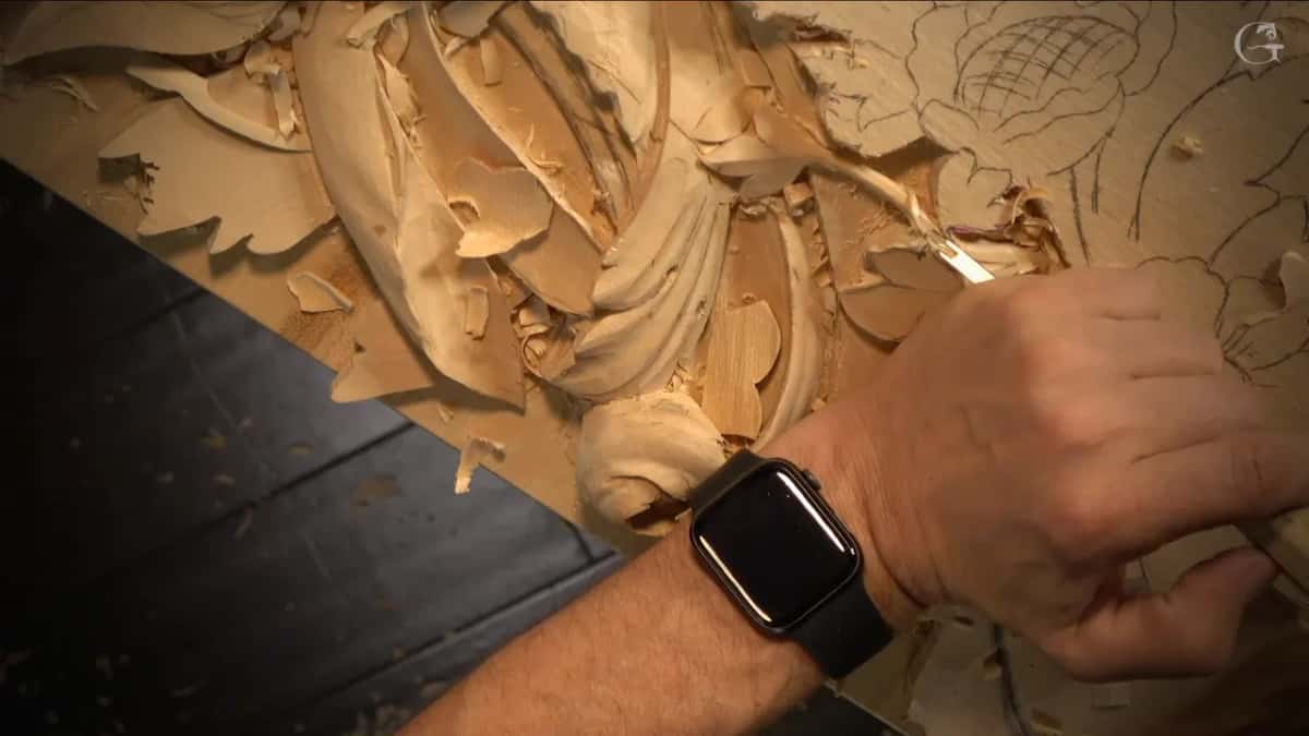 Watch on the wrist, a short gouge between the leaves, shavings everywhere on the board.