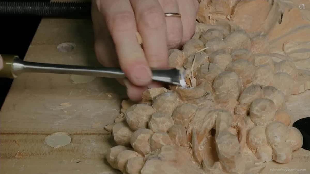 A gouge comes in from the left under a hand wearing a ring