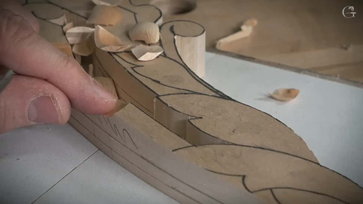 Thumb and fingers steady the blade along the edge while a curl of wood lifts off