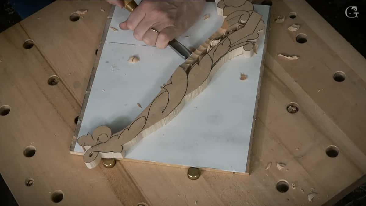 One hand drives a gouge down the outline