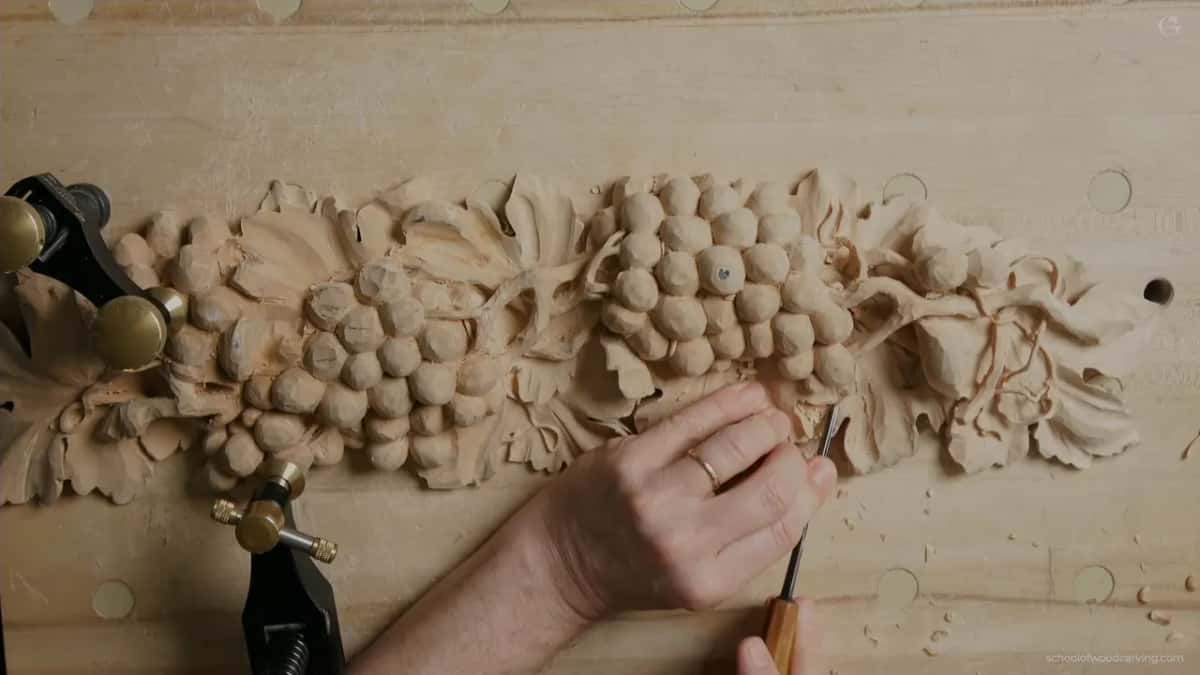 Orange handle, a gouge at a grape leaf, the onlay held face up under a clamp