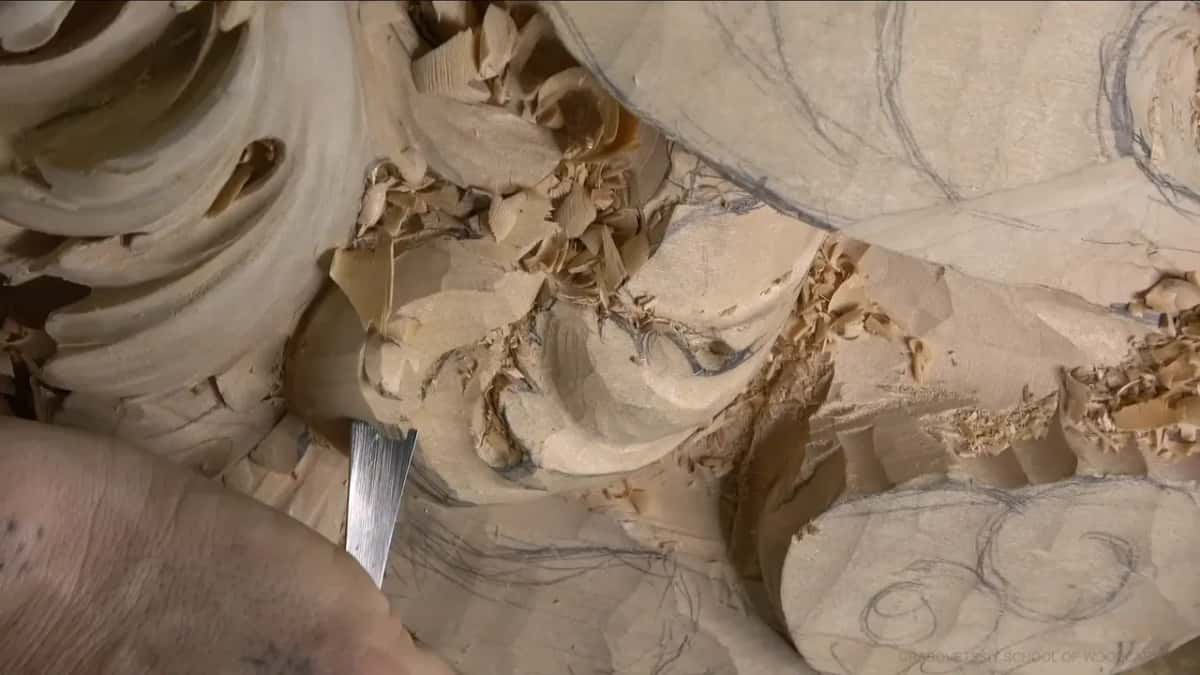 A straight flat blade stands at the foot of a lobe, with fresh chips piled in the hollow above it.