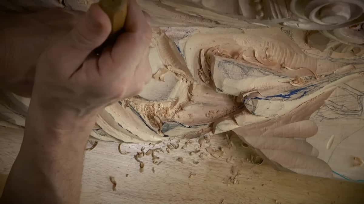 Knuckles bent around the handle while the other hand braces the board, shavings curling on the bench