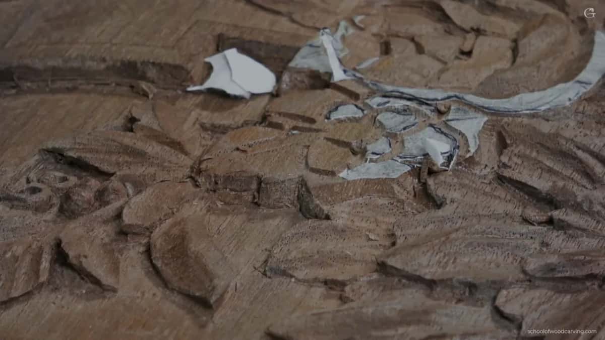 Rough first outline in the small flower with loose bits of white paper lying on the walnut