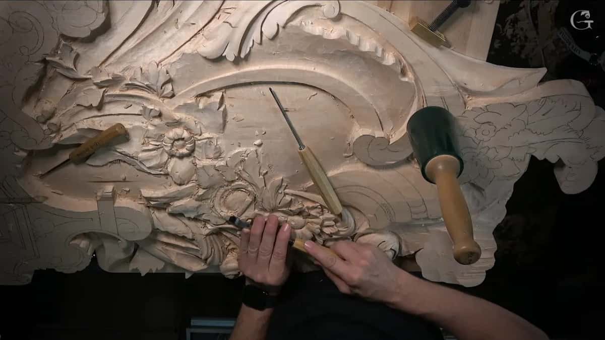 Seen from above, the whole panel with a green mallet and gouges on it, both hands at one flower