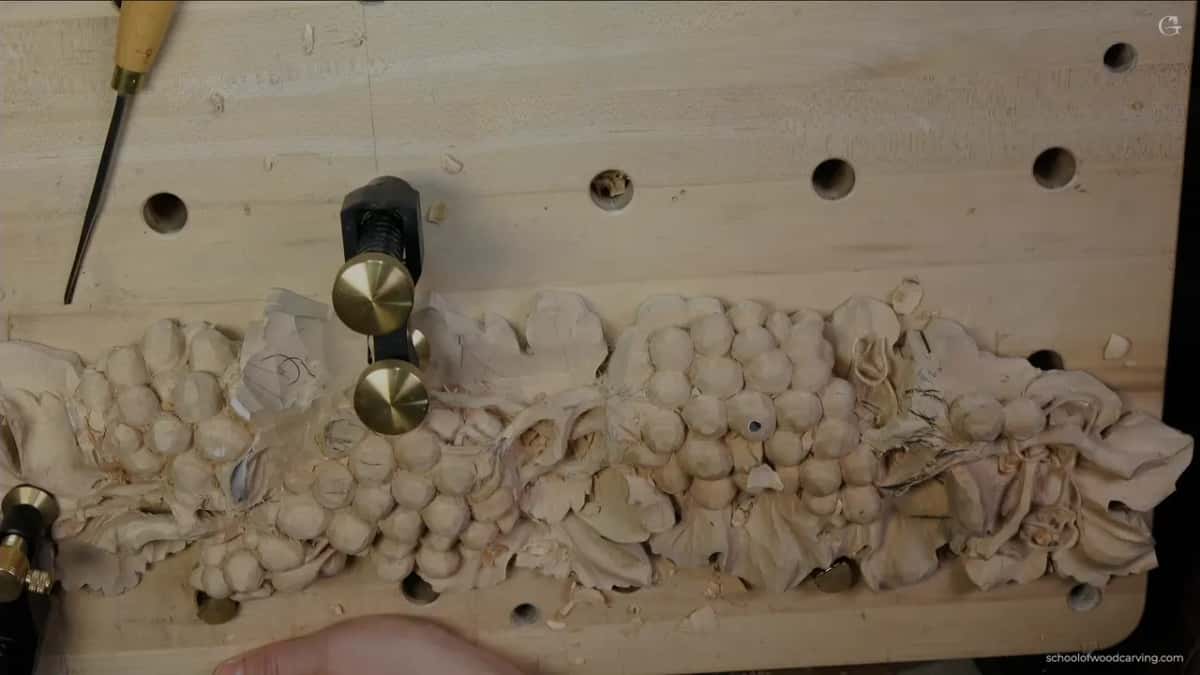 Whole panel seen from above, with a slim gouge resting on the perforated board beyond the leaves