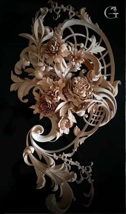 A carved flower cluster with scrolls and lattice, photographed on black