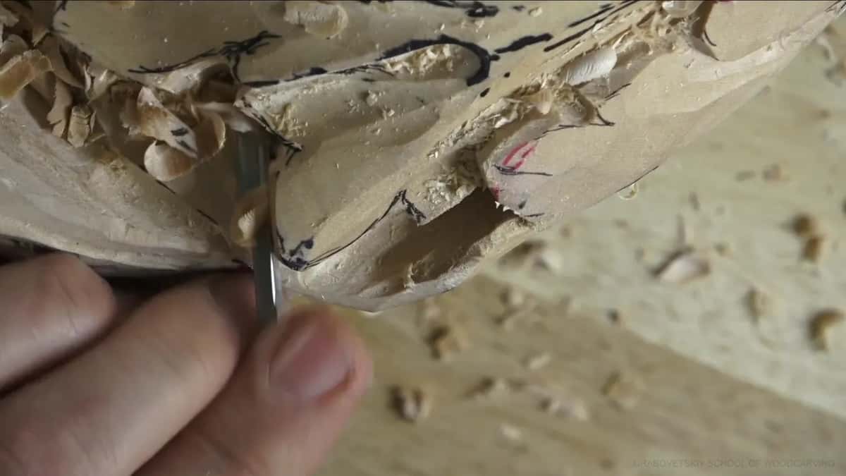 Fingertips guide a narrow tool into a dark slot.