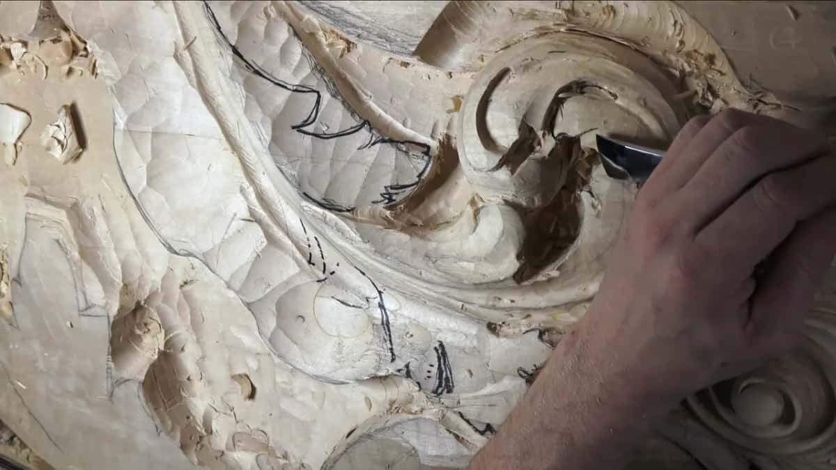 One hand reaches in from the upper right with a gouge.