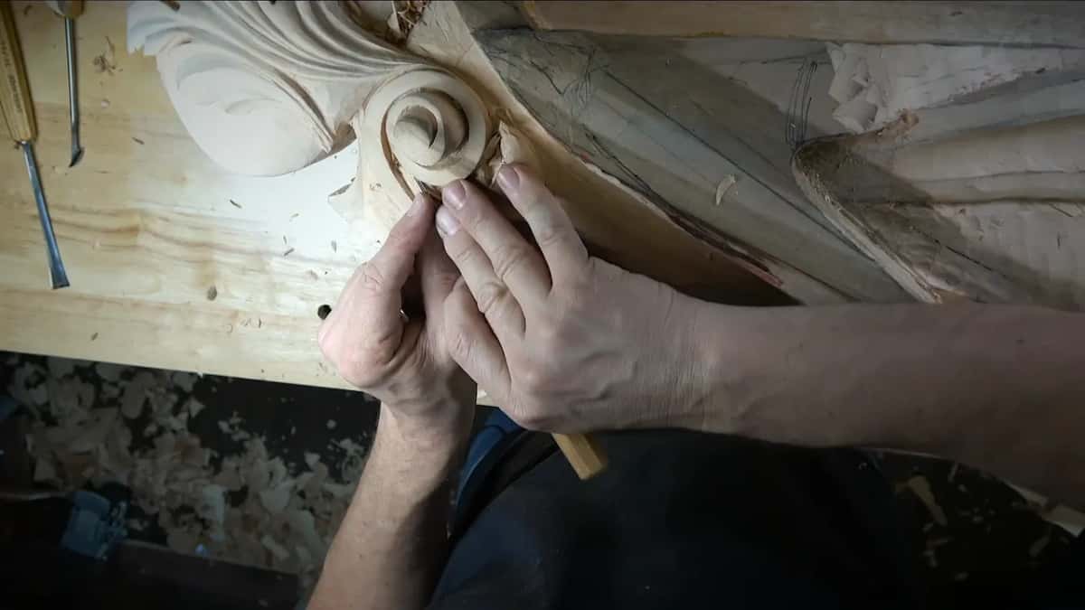 Fingertips brace a tiny tool at the base of the spiral