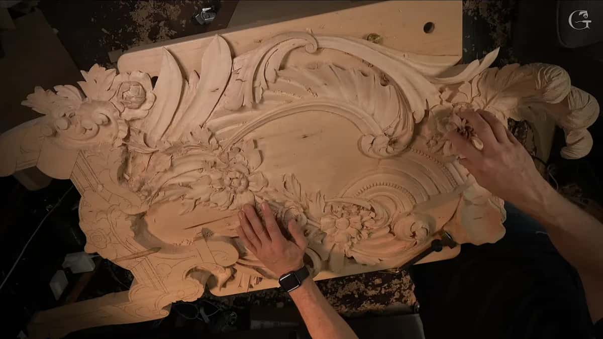 Both hands touch two different carved flowers, one high on the right and one lower in the middle of the panel