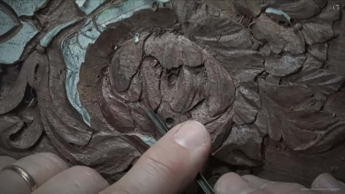 Thin tool reaching in near the dark hole, a wedding ring at the lower left