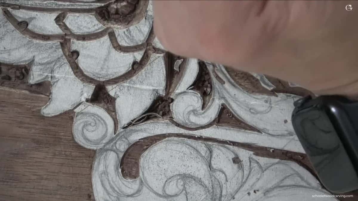 Carved leaves running into one another, a hand at the top right and a watch at the edge