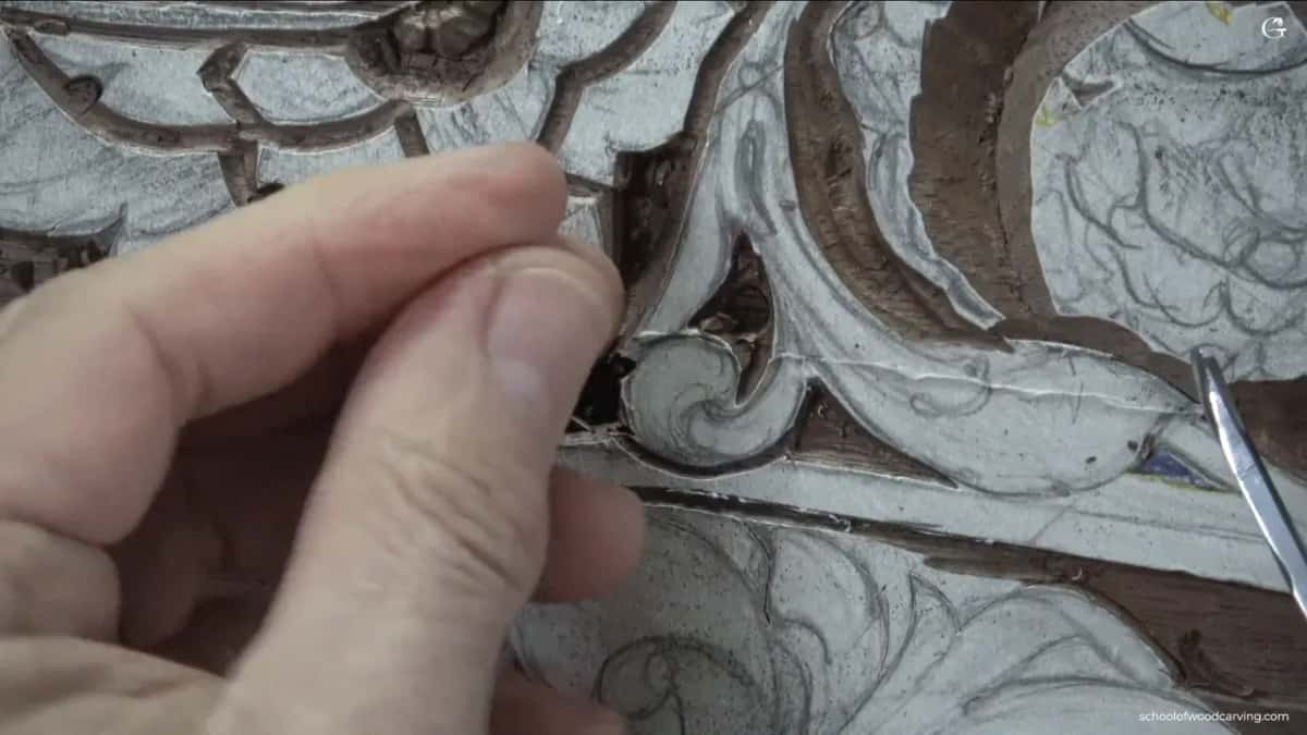 Thumb and finger pinched together over the carving