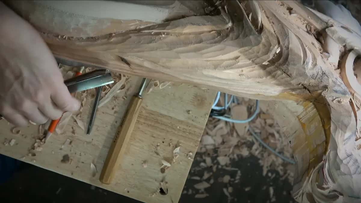 Red pencil and gouge in one hand above a board of tools