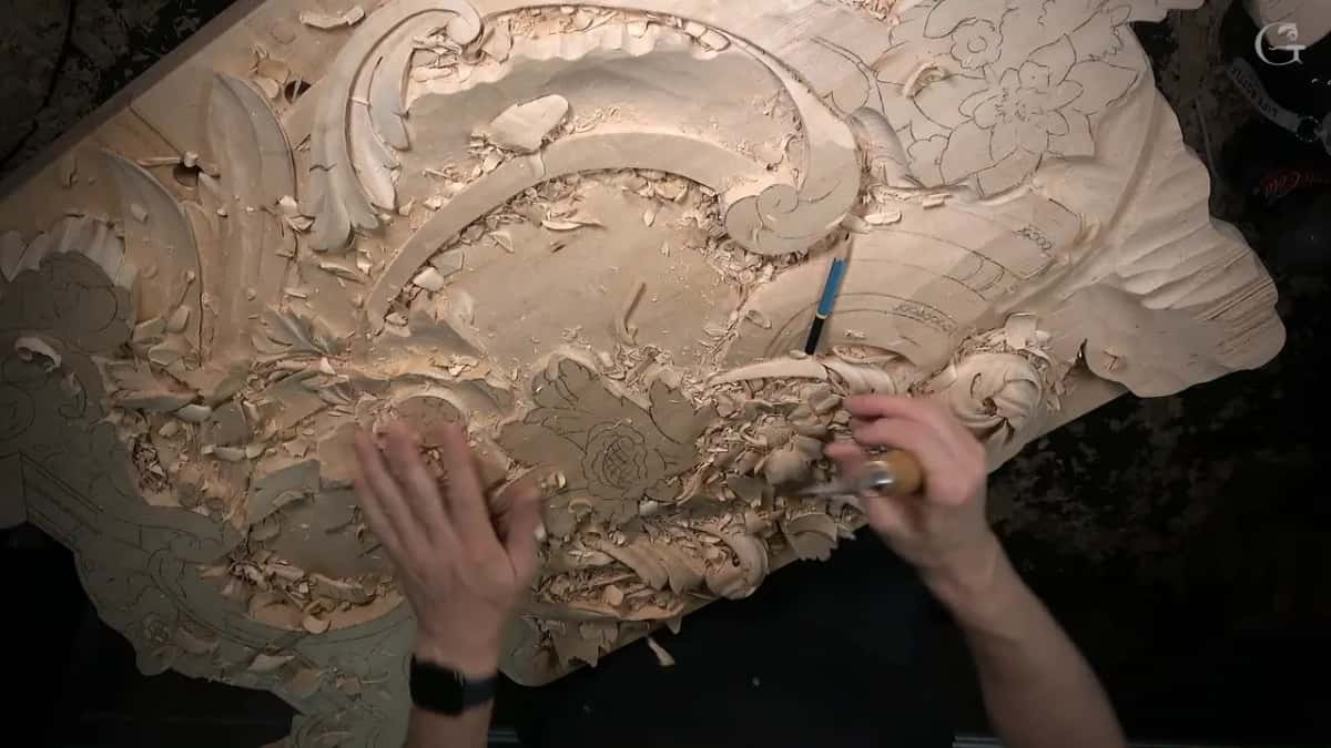 Left palm flat on the panel as the right hand brings a tool to the flower