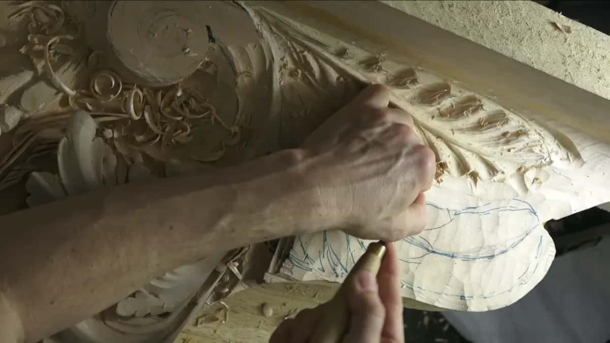 The forearm lies right across the board while the hand works the far end of the upper leaf.