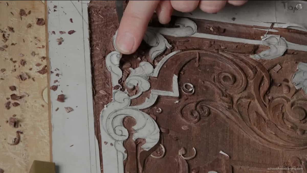 A fingertip points at the scroll while the ground around it is roughed out