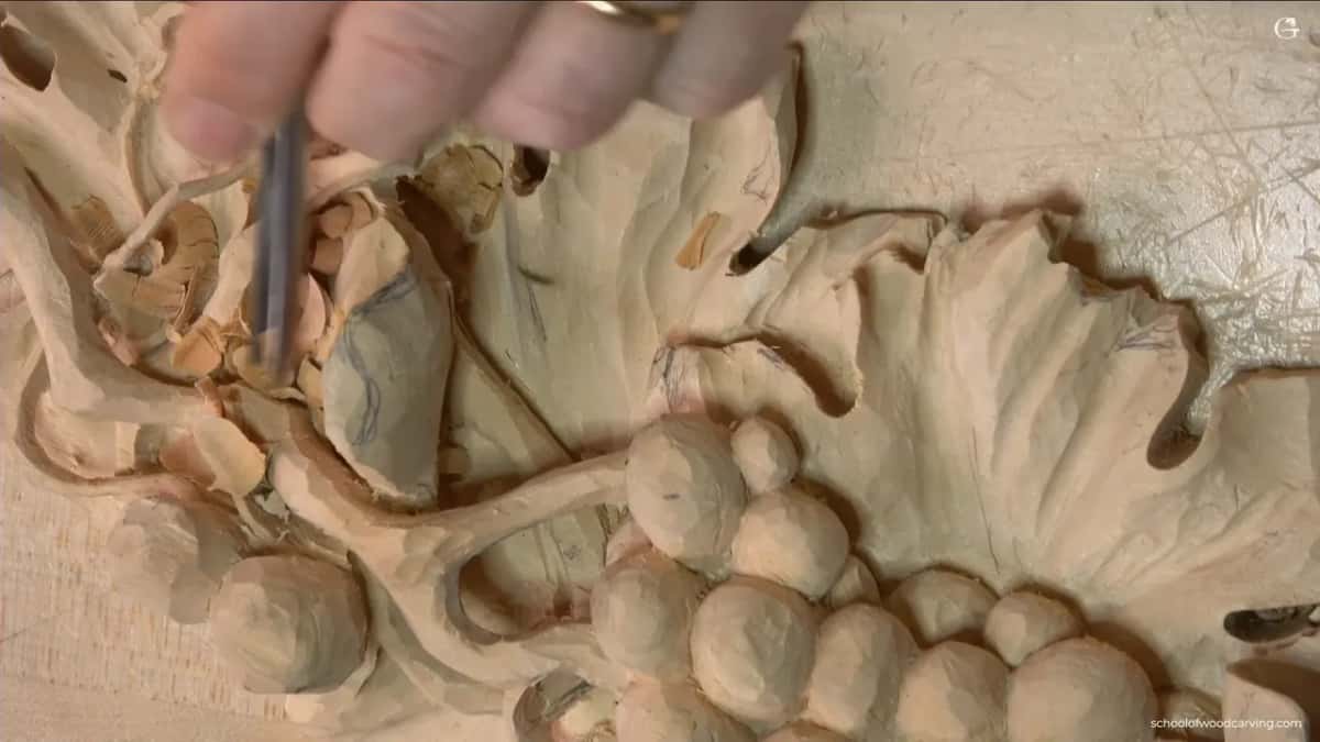 From above, a hand holds a narrow tool down into the curl, with pencil lines still on it