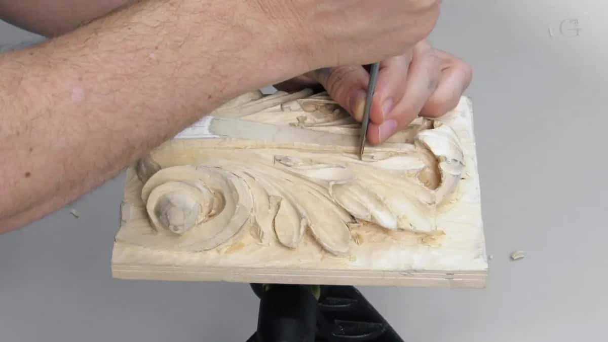A forearm crosses the frame while that hand holds a tool upright at the top of the leaf