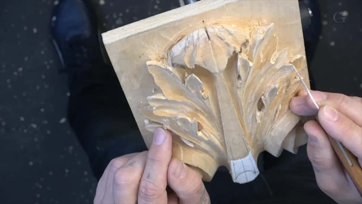 Panel propped up, fine blade brought in, both hands holding it steady against the floor
