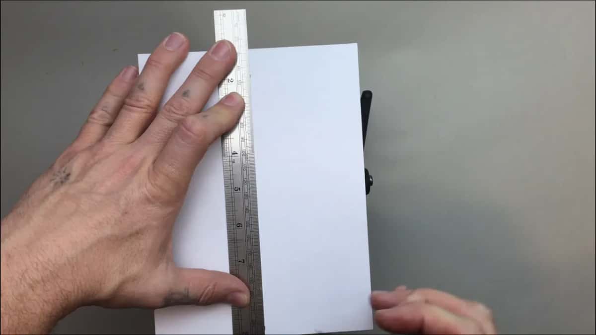 Steel rule standing up the sheet, one hand flat beside it