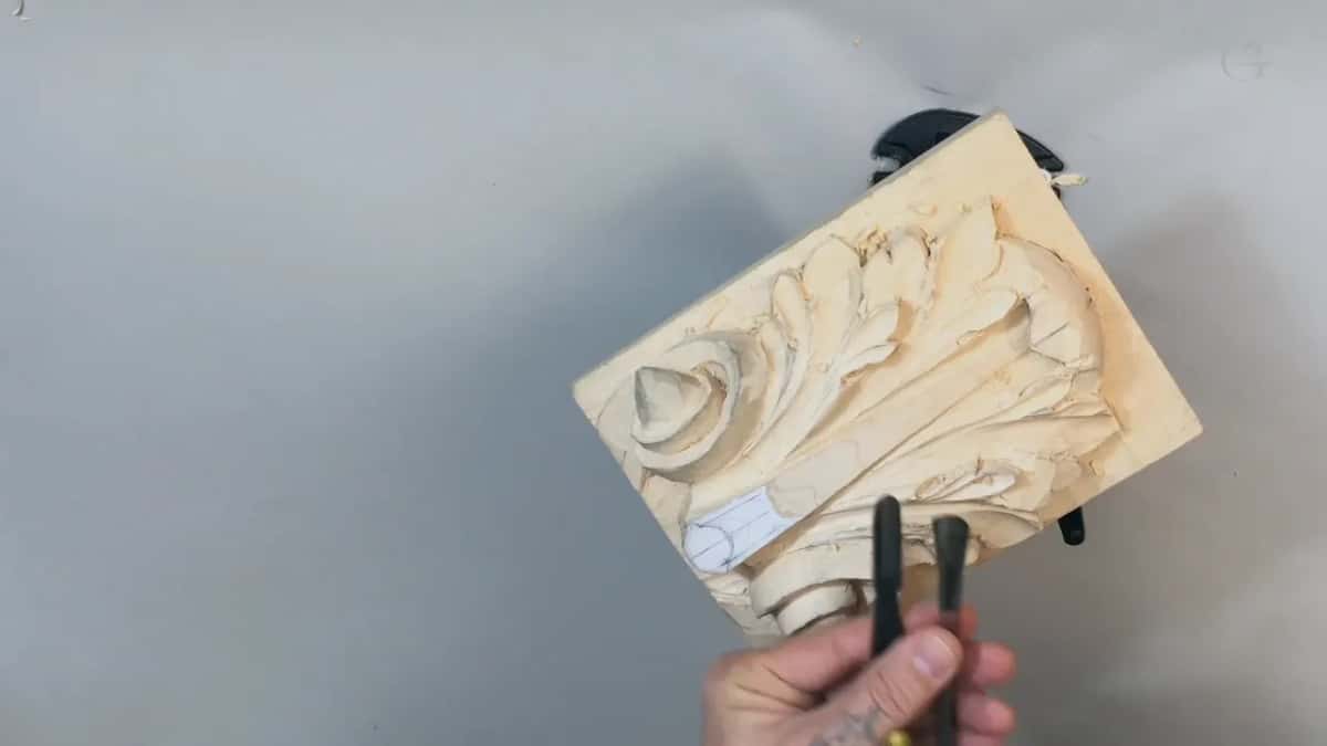 The same two dark handled gouges held up again, lower, beside the white paper on the leaf