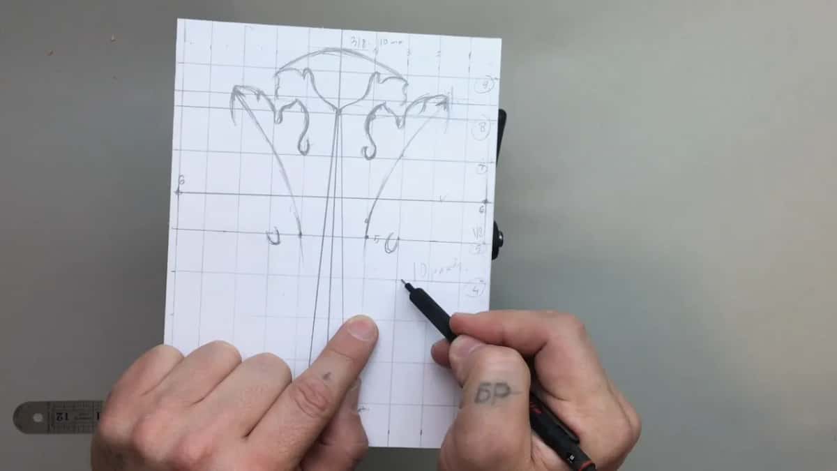 Two hands over the drawing, one finger resting on the centre line