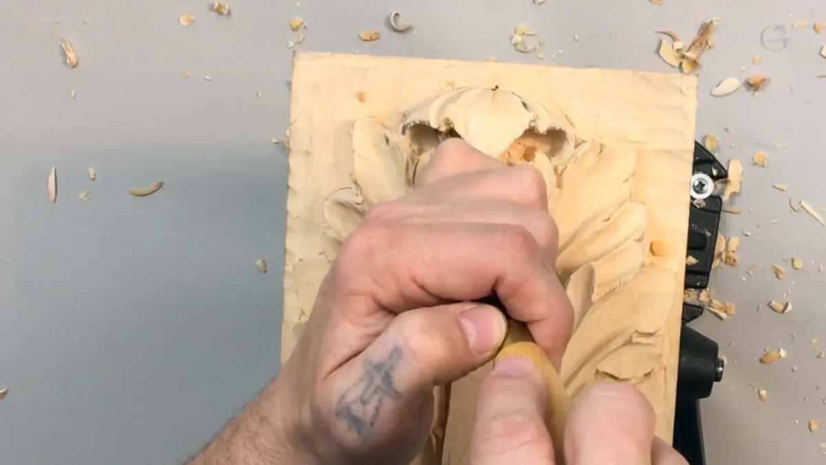 One fist dead center on the panel, shavings scattered wide across the gray table