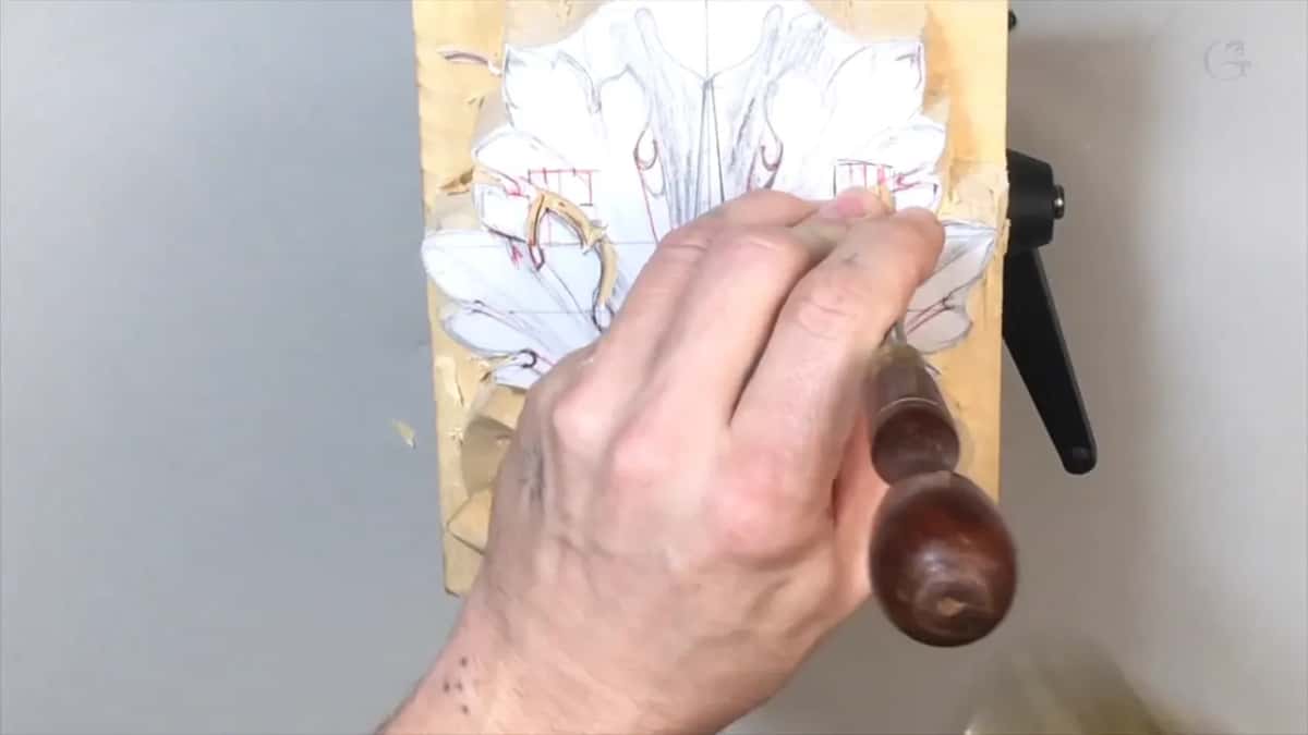 Closed fist round a dark wood handle, the blade set on the left lobes near the red hatching