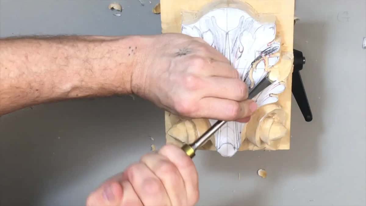Brass ferrule gouge coming up from below toward the center stem, a forearm across the top