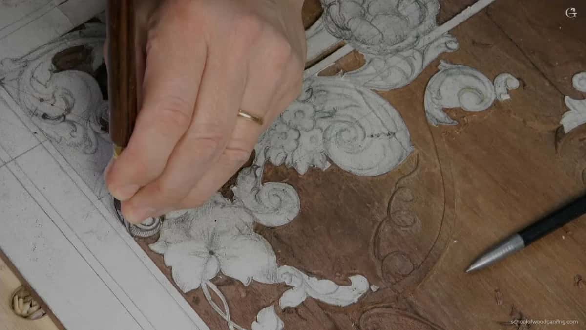 Hand with a wood-handled tool at the top left, a pen lying near the flowers