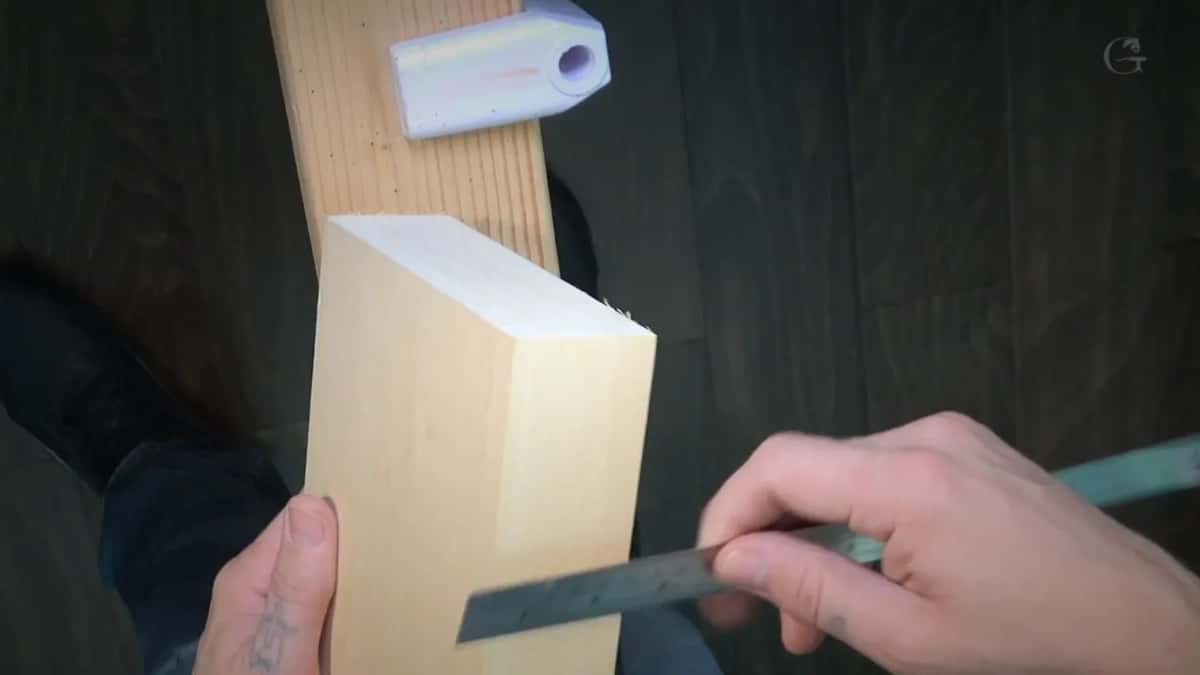 Board standing on end beside a steel rule held low in one hand