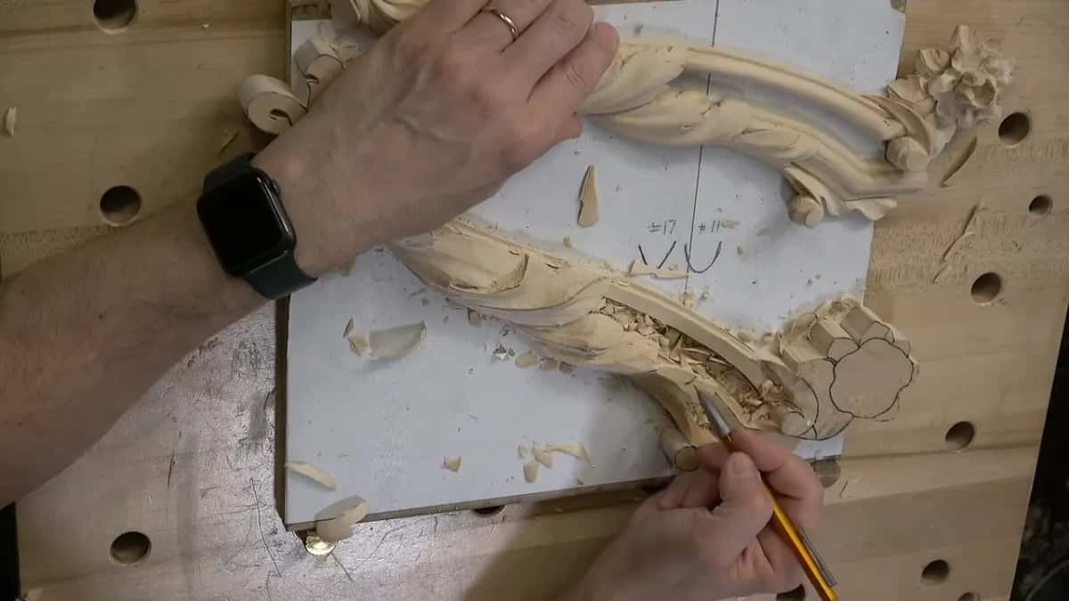 From above, one hand holds the piece steady while the other draws on it in pencil.