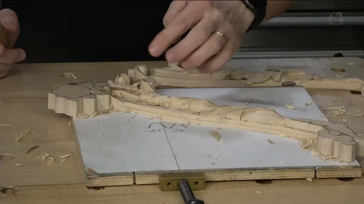 A left hand pressed flat on the carving.