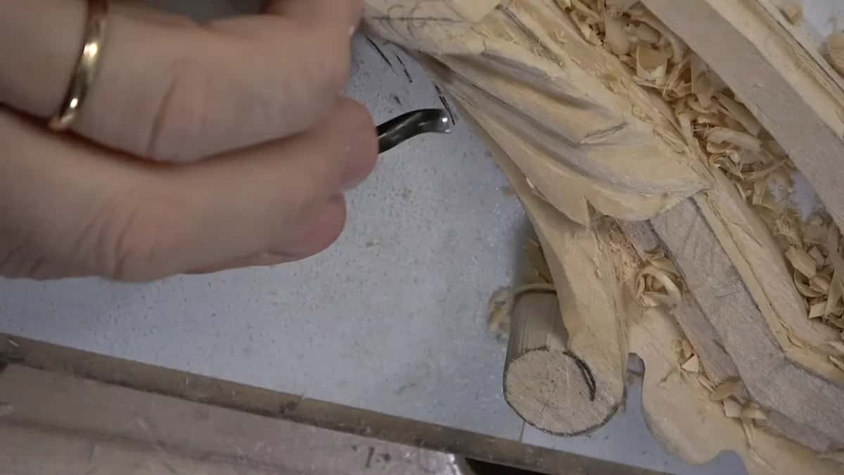 A small dark bent tool works the leaf.